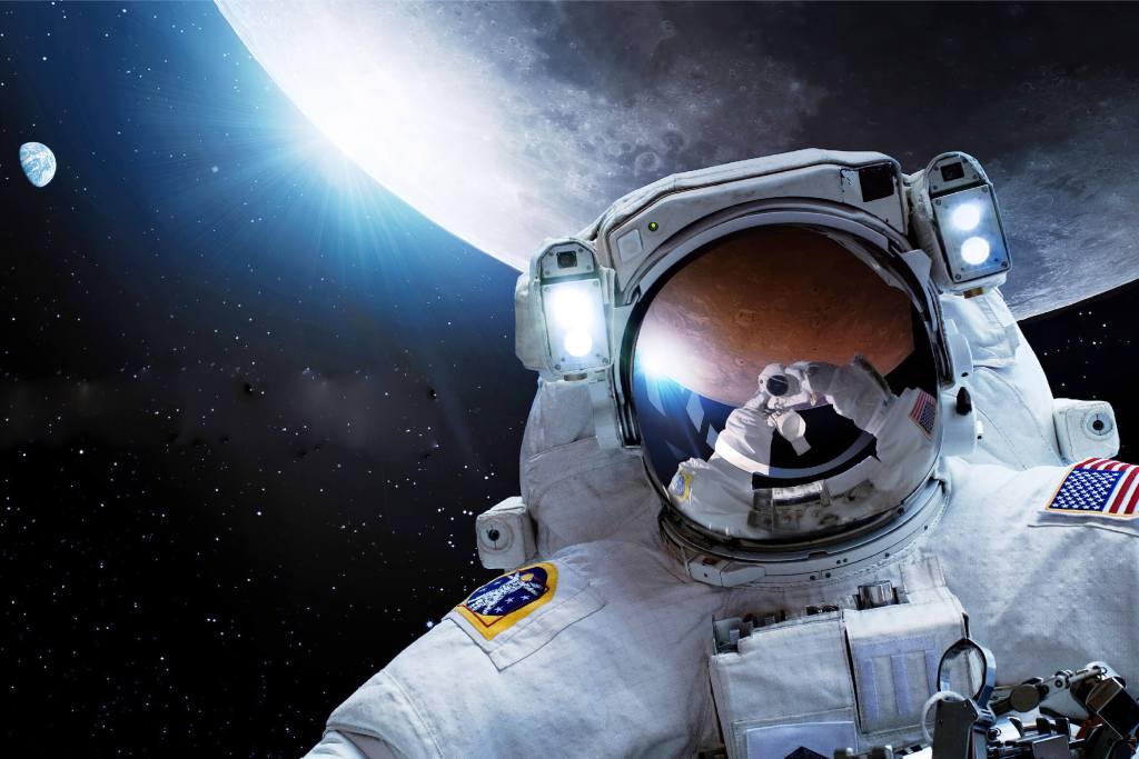 An astronaut is standing in front of the moon.