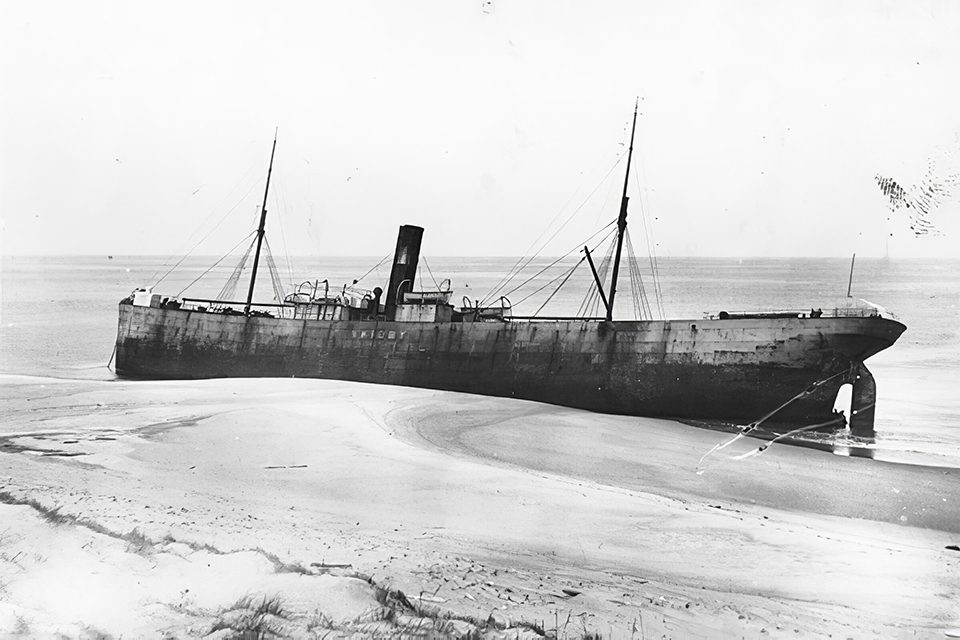 Grounded ship stranded on a sandy beach.